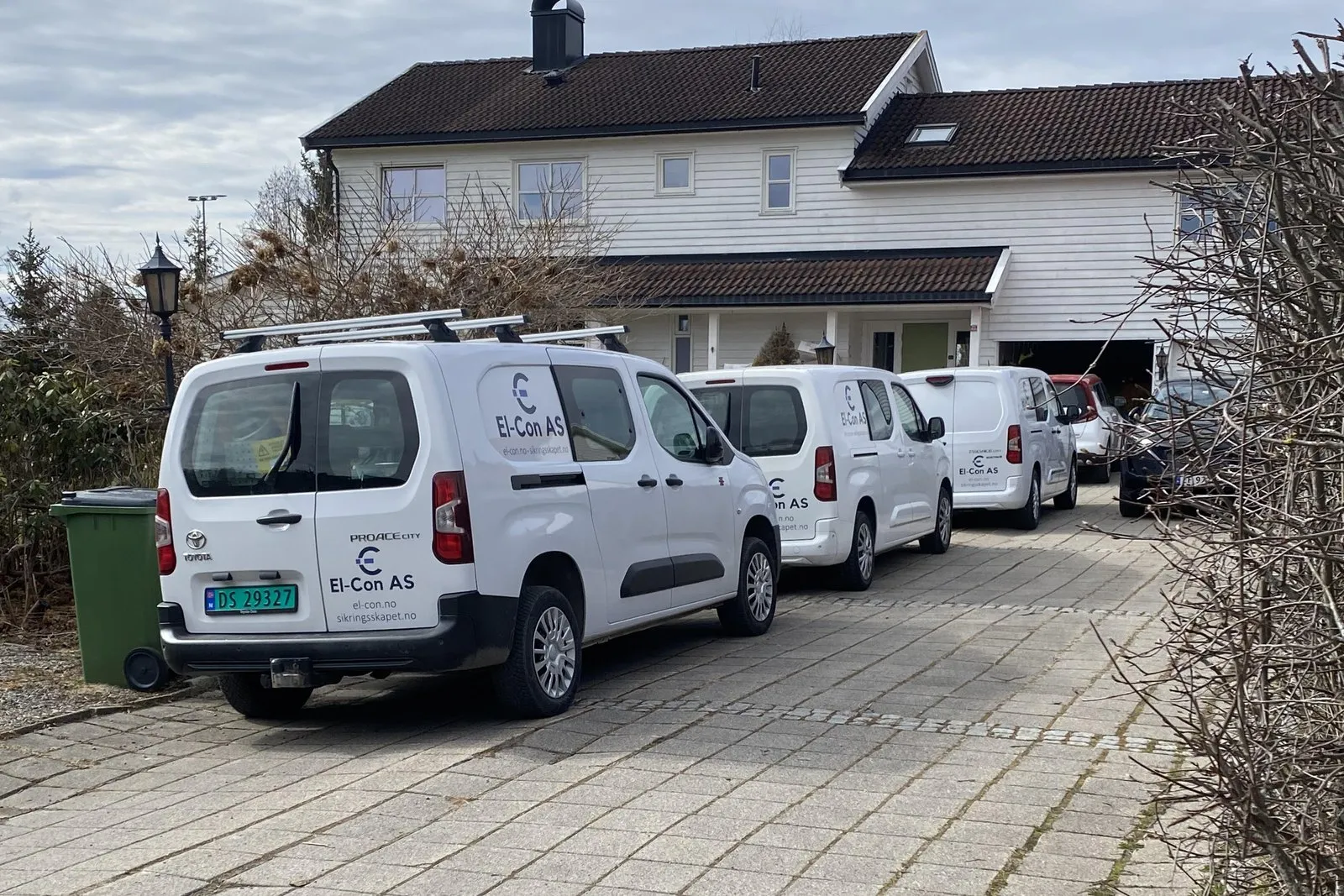 Tre servicebiler fra EL-CON AS parkert utenfor en enebolig, merket med sikringsskapet.no